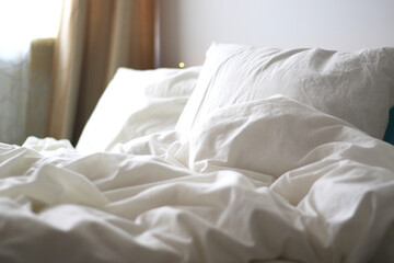 messy bed with white pillows and blanket