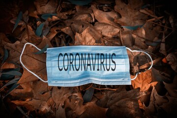 disposable protective mask on the ground of dry leaves, concept of early autumn. Coronavirus 2019. autumn landscape