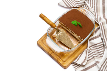 Traditional Italian Tiramisu dessert in glass baking dish on wooden cutting board isolatet on white background