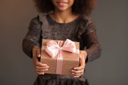 Closeup picture of cute festive girl holding a shiny gift box