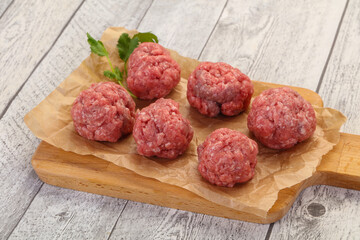 Raw meatball over wooden background