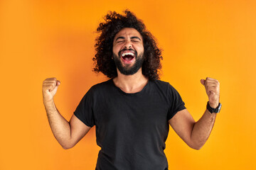 happy young indian or arab man celebrating surprised and amazed by win, winner concept. cheerful...
