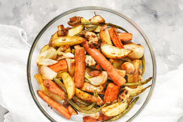 Baked vegetables on concrete background. Potatoes, carrot, mushrooms and onions.