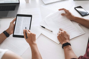 University students brainstorming on assignments using tablet and laptop at library.