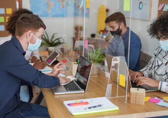 Multiracial people wearing protective face mask at work in office - Young man disinfect laptop with alcohol liquid