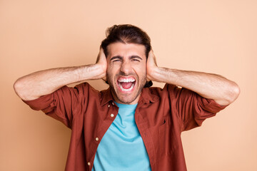 Close-up portrait of nice fury crazy emotional guy closing ears bad noise reaction isolated over beige pastel color background