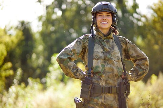 portrait of positive caucasian soldier woman smiling at camera, in nature, posing. war, hunting, military concept