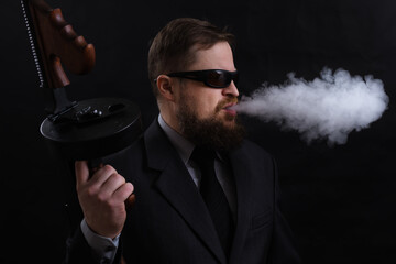 Mature bearded man in sunglasses dressed in suit with tommy gun