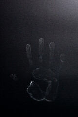 The imprint of the palm of the hand on a dark background.