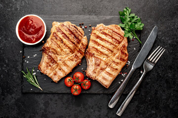 grilled pork steaks with spices on a stone background