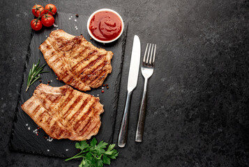 grilled pork steaks with spices on a stone background with copy space