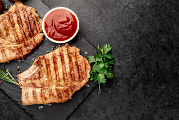 grilled pork steaks with spices on a stone background with copy space