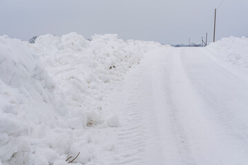 Fototapeta na wymiar Snow Piles Along Slippery Rural Road