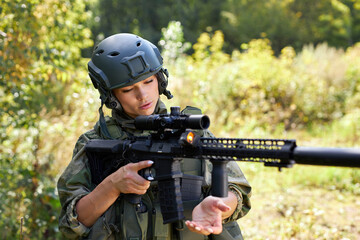 brave caucasian woman is engaged in hunting weapon gun or rifle, wearing military suit. target...