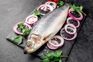 salted fish herring with onions and spices on a stone background 