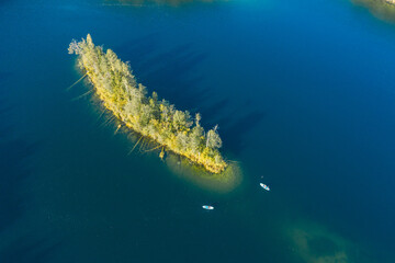 Young people ride a sup board on the lake in autumn