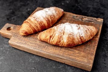 croissants on a cutting board against a stone background 