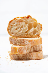 baguette cut into slices on white background, vertical closeup