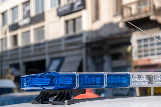 Blue light flasher at police car top, defocused city street background