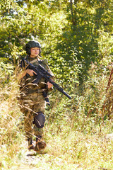 Fototapeta premium brave caucasian woman is engaged in hunting weapon gun or rifle, wearing military suit. target shot. female hunter in wild forest, nature. successful hunt. hunting sport concept