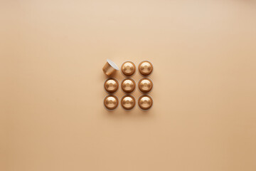 Caffeine, hot drinks and objects concept - close up of golden capsules or pods for coffee mashine on beige background. Top view with space for text. Flat lay..