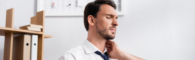 Obraz premium Businessman holding hand on aching neck, while looking away in office, banner