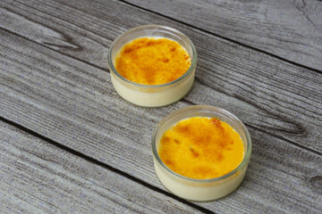 Crème brûlée on wooden table .Delicious dessert famous in France , similar as Spanish 'Crema catalana' .