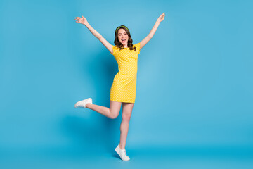 Fototapeta na wymiar Full body photo of girlish enthusiastic young girl raise hands leg isolated over blue color background