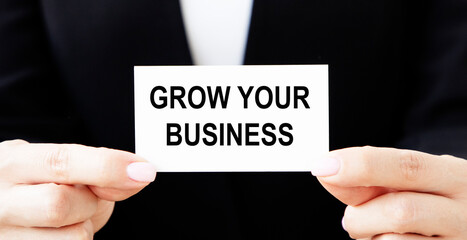A businessman puts a card in his pocket with the text GROW YOUR BUSINESS.