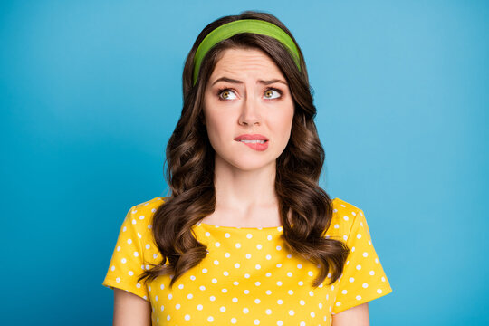Photo of frustrated girl look empty space bite lips teeth thinking problem isolated over blue color background
