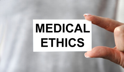 The girl holds a business card in front of her with the text MEDICAL ETHICS.