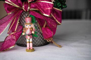 Frosted vintage pink miniature wooden toy soldier is centerpiece of this beautiful pink poinsettia in a silver metal container with fuchsia and gold ribbon. 