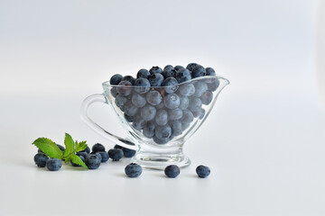 Fresh blueberries with mint leaves. Freshly picked blueberries in glass on white background. Healthy organic seasonal fruit background. Berries closeup.Selective focus