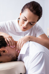 Obraz na płótnie Canvas Close up view of positive masseuse doing neck massage for client