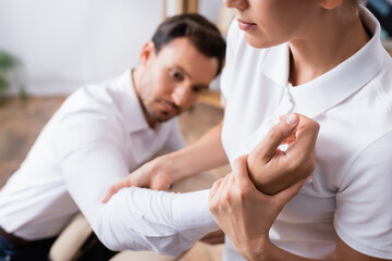 Fototapeta premium Masseuse doing arm massage for businessman on blurred background