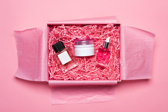 Beauty box with cosmetics filled with shredded pink paper packing material. Delivery of fragile object. Background and copy space