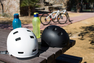black and white bicycle helmets with water bottles and bikes in the background