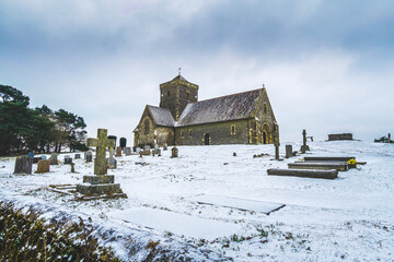 St Martha's Church on the Hill on a cold winter's day with snow covered graveyard and dark moody clouds