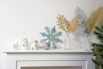 Christmas decoration: blue faux glitter snowflake, candle holder and porcelain white figurine bullfinch bird stand on the console.