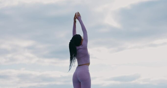 Shot back young African american woman doing yoga poses meditation in mountains. Harmony concentration activity nature healthy. Relaxation. Slow motion