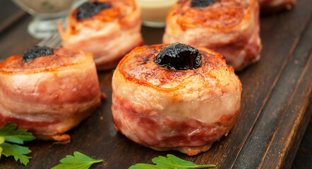 Meat medallions with prunes are served on a wooden board. Meat dishes. Close-up. Copy space.