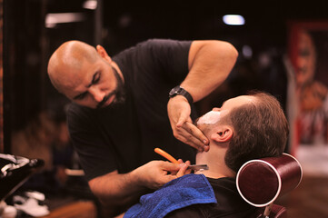 Brutal barber shaves a man in a barbershop