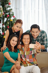 Happy mature Asian men and women taking selfie at Christmas party