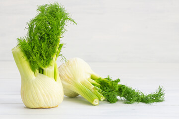 Fresh organic fennel bulbs on white wooden background, fragrant herbaceous plant, healthy vegetable concept (Foeniculum vulgare)