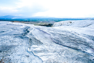 grey textured travertine hill with blue-white cloudy sky - Pamukkale.