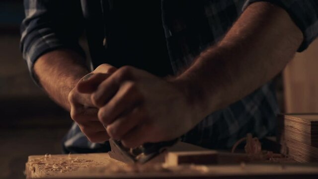 Carpenter cutting off wooden shavings with jointer