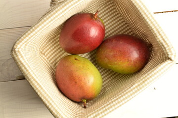 ripe mangoes, close-up, on a white wooden table.