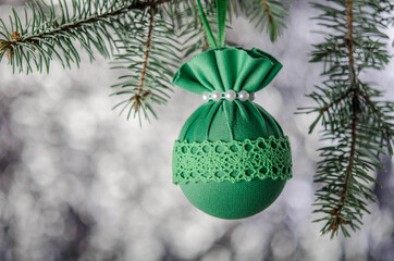 One green Christmas ball on a green spruce branch.