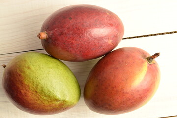 ripe mangoes, close-up, on a white wooden table.