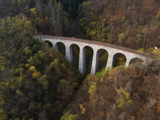 Aerial top view of stone Railway Viaduct near Prague, Czech republic. Old Czech railway line. Vintage arch bridge during autumn season.